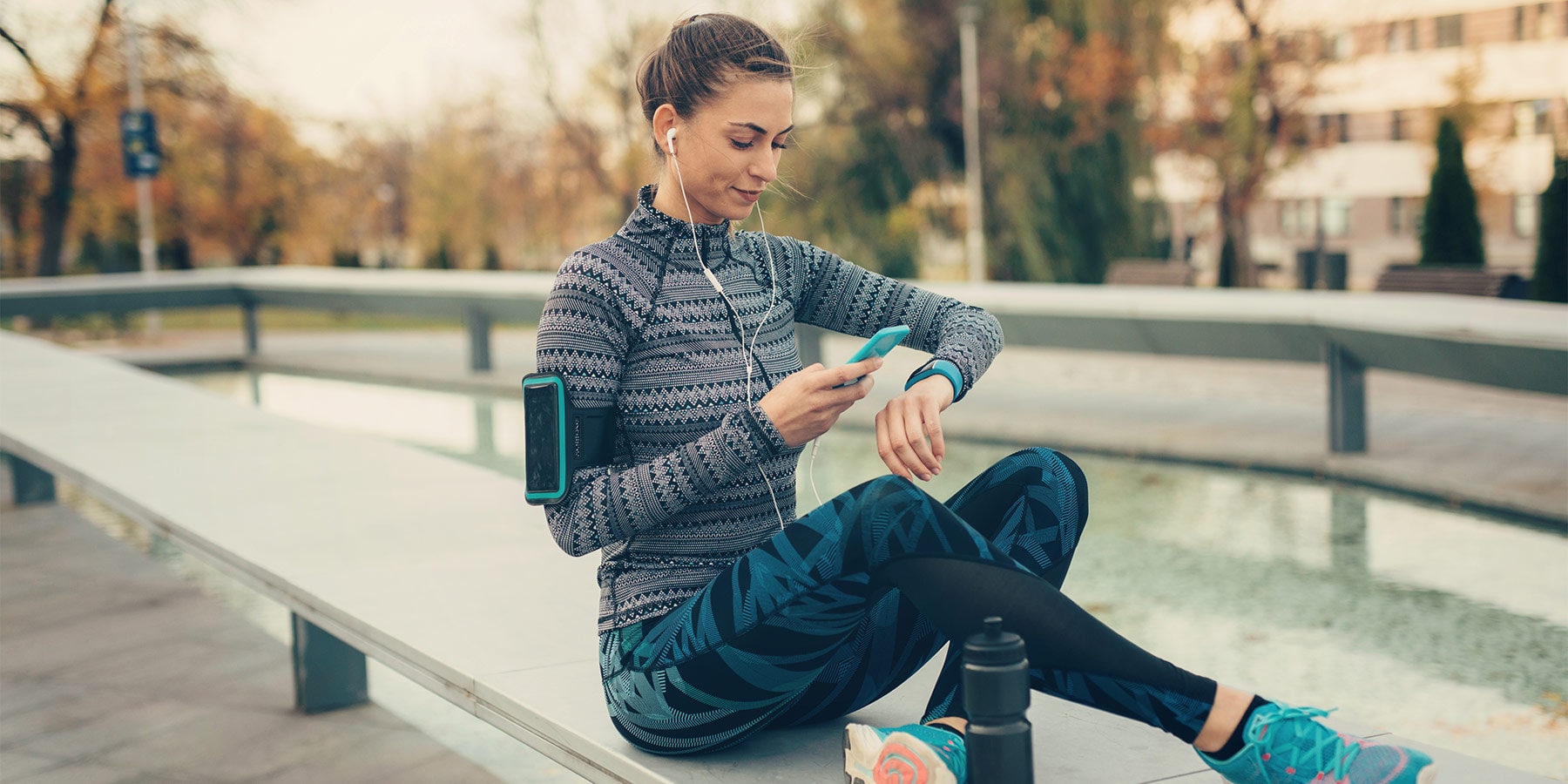Woman in exercise gear sitting on bench looking at smart phone